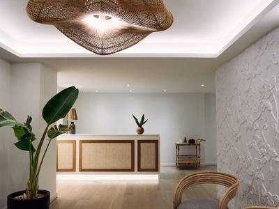 Modern hotel lobby with illuminated reception desk and plants in a stylish setting.