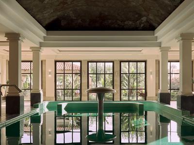 Indoor pool with green benches and large windows in a hotel.