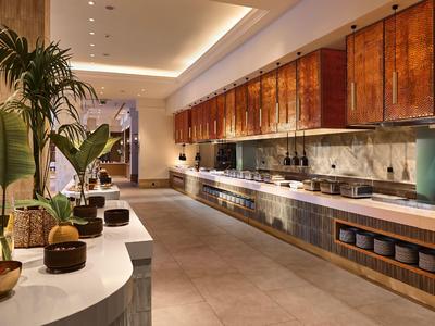 Modern hotel kitchen with long countertops, wooden cabinets, and subtle lighting design.