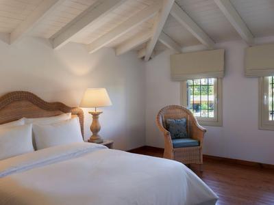 Gemütliches Schlafzimmer mit weißem Bett und Holzmöbeln unter schrägem Dach.