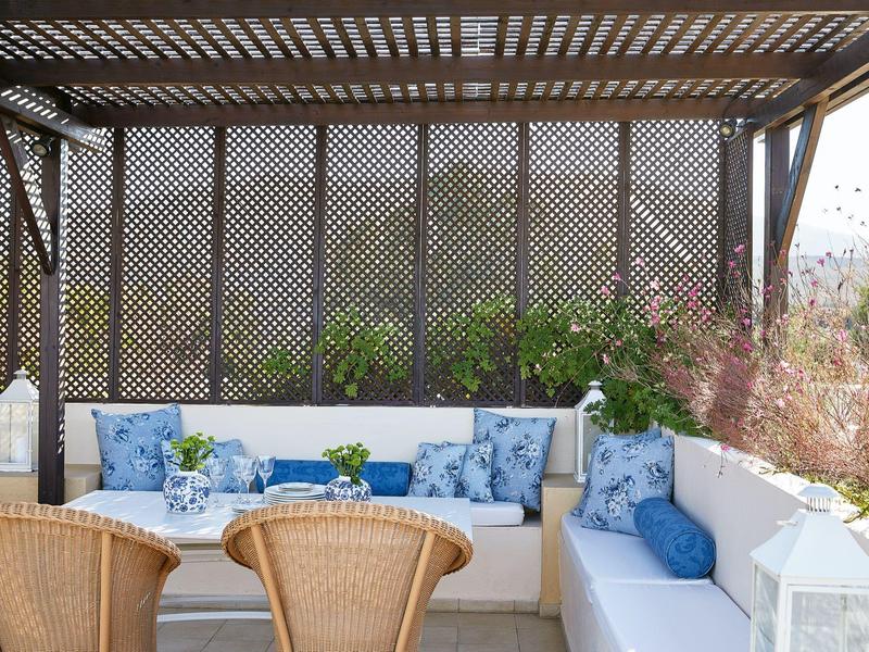 Cozy outdoor seating area with blue cushions and wicker chairs under a wooden pergola.