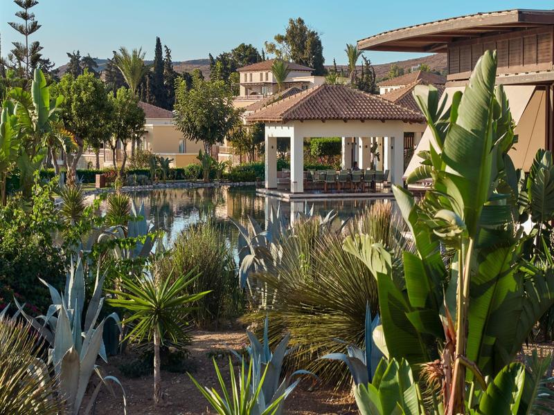 A tropical hotel resort with a pavilion by the water and lush vegetation.
