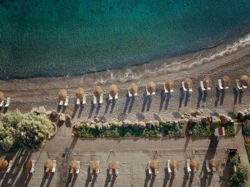 Aerial view of a beach with evenly arranged sun umbrellas and lounge chairs.