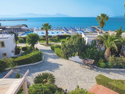 Blick auf einen Hotelgarten mit Palmen und Blick auf den Strand und das Meer im Hintergrund