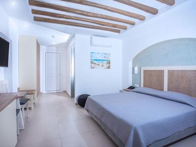 Helles Hotelzimmer mit blauem Bett, Holzdeckenbalken und Flachbildfernseher.