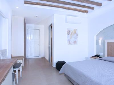 Helles Hotelzimmer mit Doppelbett, Holzbalken und Schreibtisch mit Stühlen