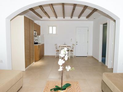 Blick durch einen Bogen in einen einfachen, hellen Wohn- und Küchenbereich mit Holzbalkendecke.