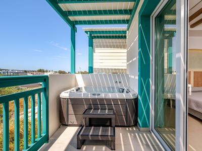 Balkon mit Whirlpool, grünem Geländer und Blick auf Außenbereiche eines Hotels.