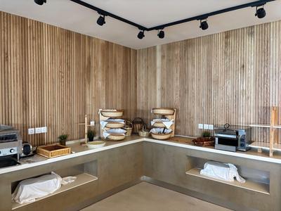 Modern eingerichtete Küchenzeile mit Holzpaneelen, Toastern und Regalen in einem Hotelraum.