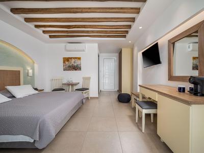Hell eingerichtetes Hotelzimmer mit Doppelbett, Schreibtisch, Fernseher und Klimaanlage.