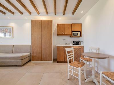 Moderner Hotelzimmerbereich mit Sofa, Küchenschrank und rundem Essbereich mit zwei Stühlen.