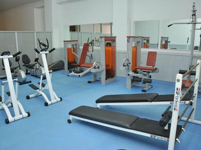 Fitnessraum mit verschiedenen Trainingsgeräten und blaum Bodenbelag in einem Hotel.