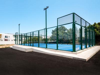 Moderner, umschlossener Tennisplatz mit blauem Boden und umliegendem Glaszaun.