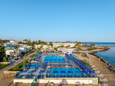 Große Hotelanlage mit mehreren Pools und Blick auf das Meer bei klarem Himmel.