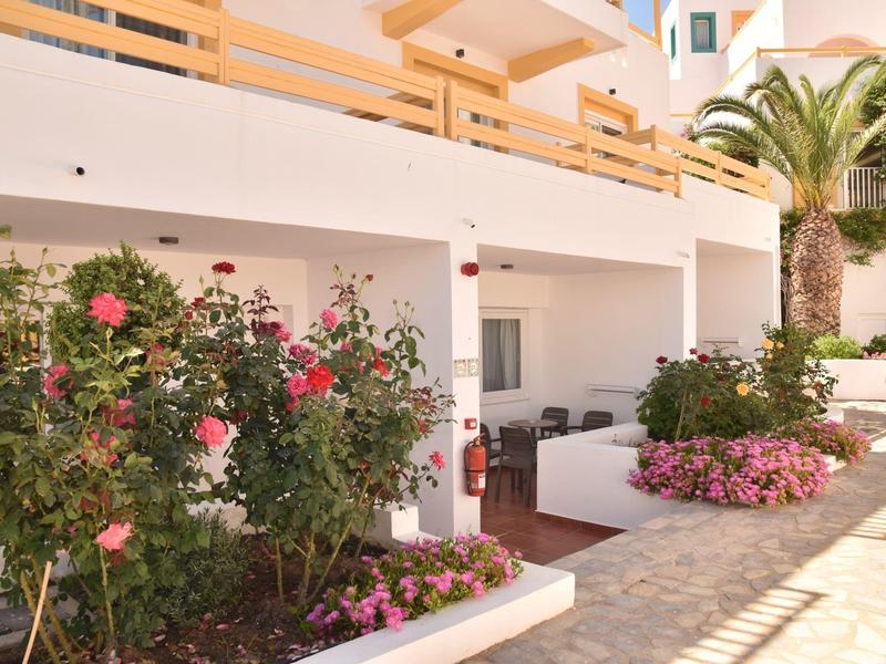 Moderner Außenbereich mit weißer Mauer, blühenden Pflanzen und Sitzbereich neben Palmen