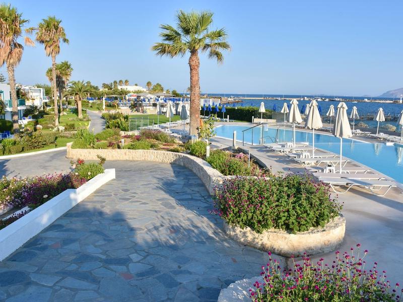 Weitläufige Hotelanlage mit Palmen, Pool und Meerblick bei klarem Himmel.