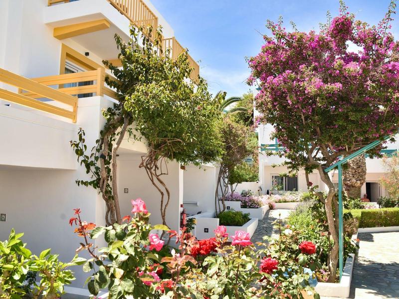 Ein heller Innenhof mit blühenden Bäumen und Sträuchern vor weißen Gebäuden bei sonnigem Wetter.