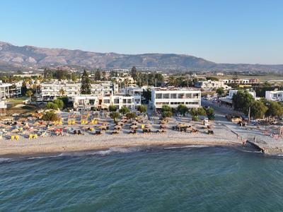 Plaża z leżakami przed hotelem i górami w tle.