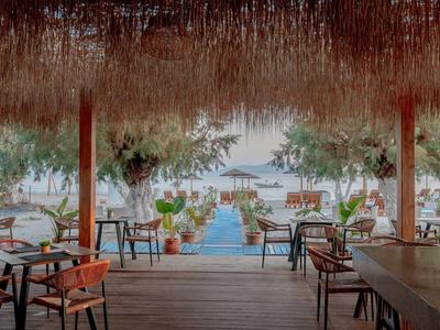 Tropikalny bar na plaży z miejscami do siedzenia, widokiem na morze i łodzie na wodzie.