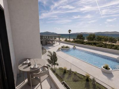 Balkon mit Tisch und zwei Stühlen mit Blick auf einen Pool und Hügel im Hintergrund.