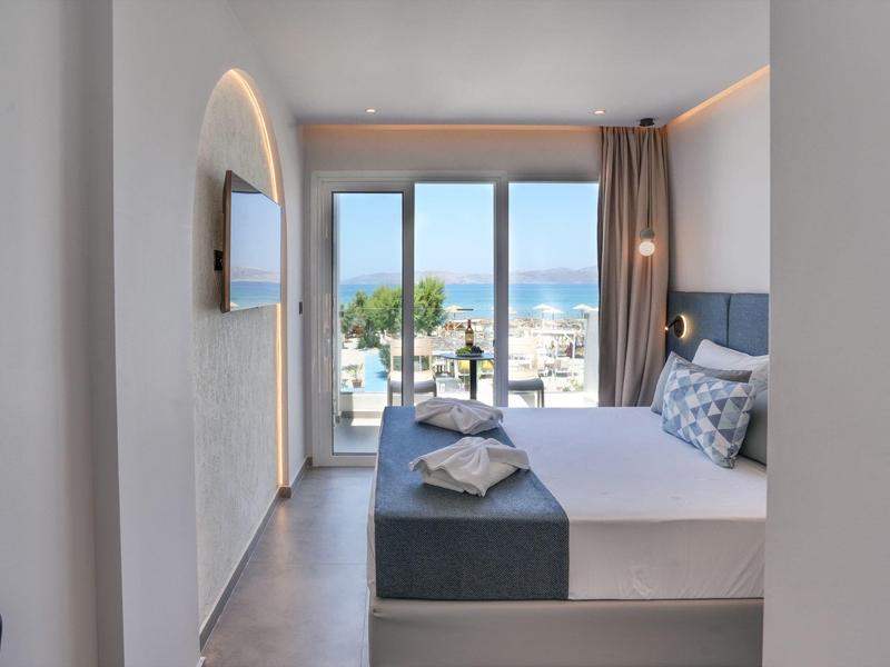 Modernes Schlafzimmer mit großem Bett, Glasfenstern und Meerblick, helle Wände und dezente Deko.