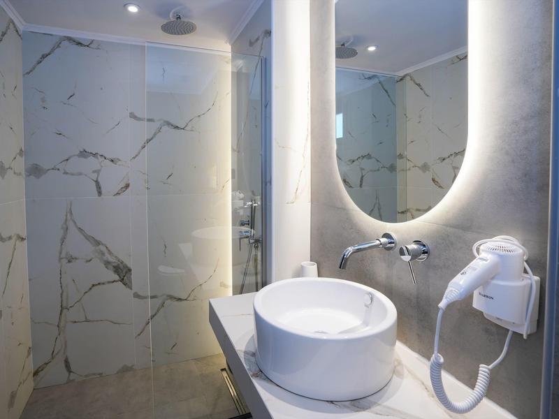 Modernes Badezimmer mit weißem Marmor, Rundwaschbecken und großer ovaler Spiegelbeleuchtung.