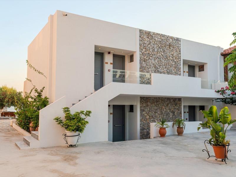 Modernes weißes Ferienhaus mit Balkon und Topfpflanzen im einladenden Innenhof.