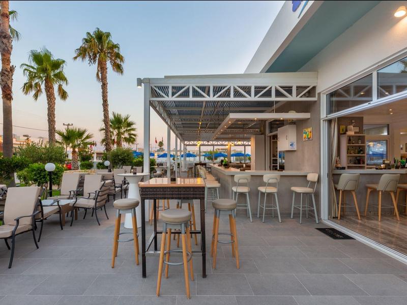 Nowoczesny teren zewnętrzny baru hotelowego z miejscami do siedzenia i palmami o zachodzie słońca.