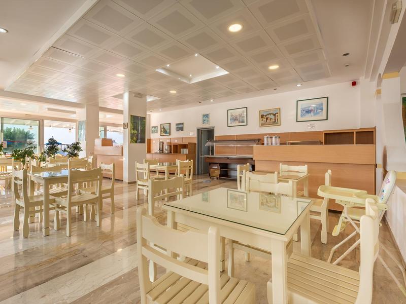 Jasna sala jadalna w hotelu z drewnianymi krzesłami, stołami i zdjęciami na ścianach.