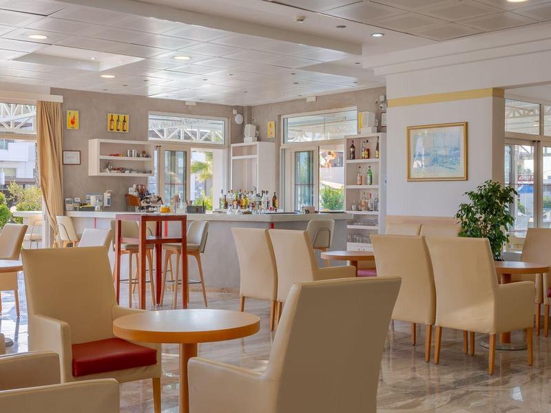 Jasna, nowoczesna kawiarnia z wygodnymi krzesłami, stołami i dużymi oknami z widokiem na zieleń.