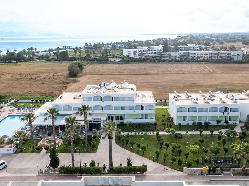 Kompleks hotelowy z basenami, palmami i miejscami parkingowymi w słoneczny dzień