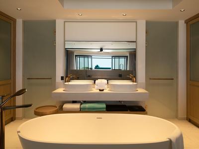 Moderní koupelna s volně stojící vanou, dvojitým umyvadlem a velkým zrcadlem.