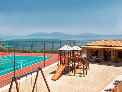 Venkovní dětské hřiště a tenisový kurt s výhledem na moře a hory.