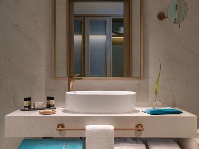 Moderní koupelna s velkým zrcadlem, umyvadlem, ručníky a pantoflemi.