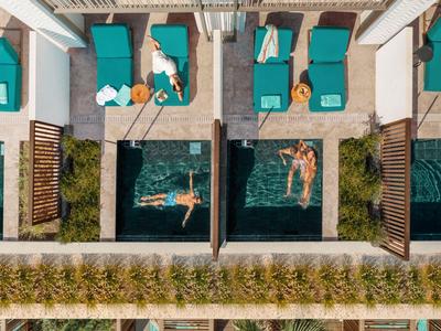 Vogelperspektive eines Resorts mit Pools und Liegestühlen neben grünen Pflanzen.