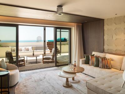 Modern eingerichtetes Wohnzimmer mit Sofa und Blick auf Terrasse und Meer.