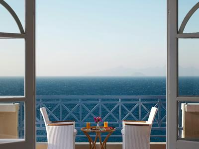Vista desde la terraza con dos sillas y una mesa pequeña frente al mar azul.