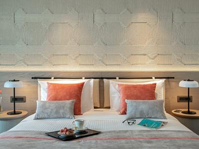Dormitorio moderno con cama doble, cojines decorativos y elegantes lámparas de noche.
