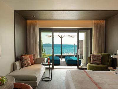 Habitación de hotel moderna con vistas al mar y zona de estar en el balcón.