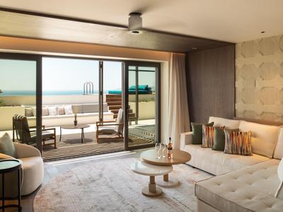 Confort moderno de hotel con vista a la terraza y al mar en el horizonte.