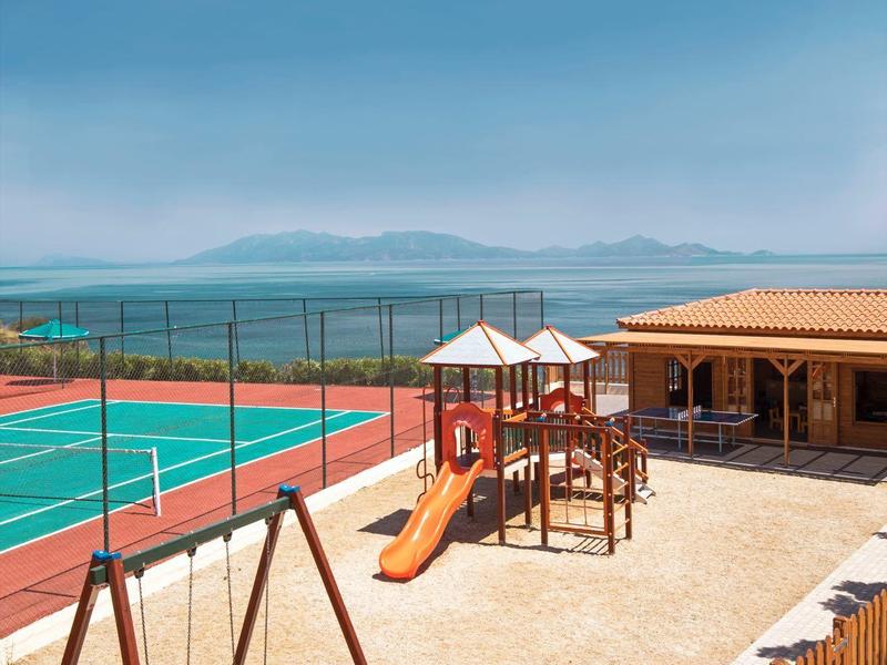 Venkovní dětské hřiště a tenisový kurt s výhledem na moře a hory.