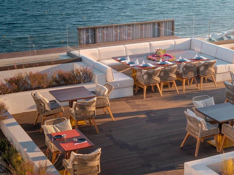 Venkovní posezení s stoly a židlemi s výhledem na moře během dne.