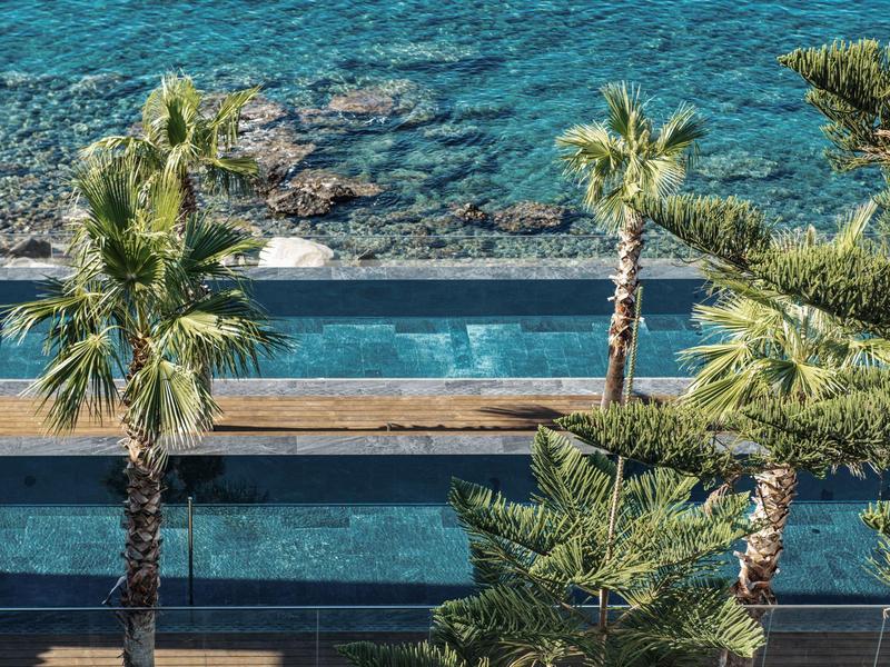 Pohled na vícestupňový bazén s průzračně modrou vodou a palmami kolem