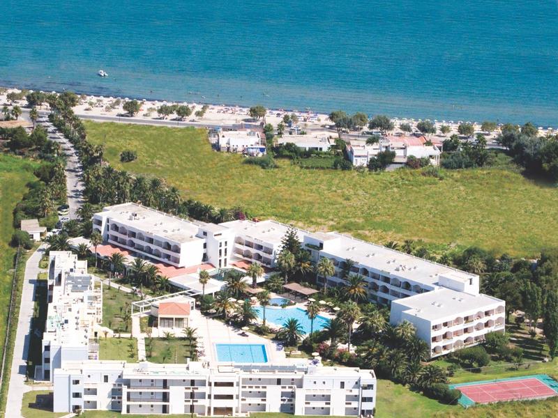 Letecký pohled na hotel s bazény poblíž pláže a moře v pozadí.