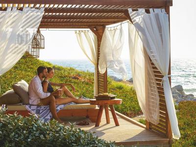 Paar sitzt entspannt in einer überdachten Lounge mit Blick aufs Meer.