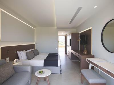 Moderní hotelový pokoj se dvěma manželskými postelemi, posezením a velkým zrcadlem na zdi.