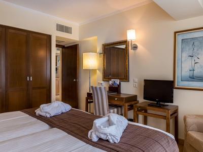 Příjemný hotelový pokoj s manželskou postelí, psacím stolem, televizí a elegantním dekorací.