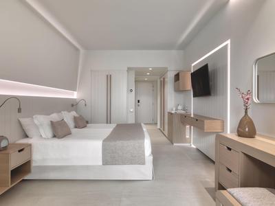 Moderně zařízený hotelový pokoj s velkou postelí, televizí a světlým interiérem.