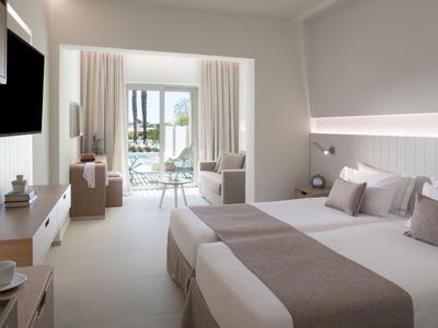 Modernes Hotelzimmer mit zwei Betten, Sitzbereich und Balkon mit Meerblick.