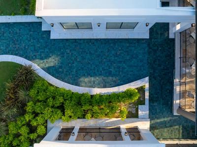 Vogelperspektive auf einen modernen Pool neben einem weißen Gebäude mit Begrünung.